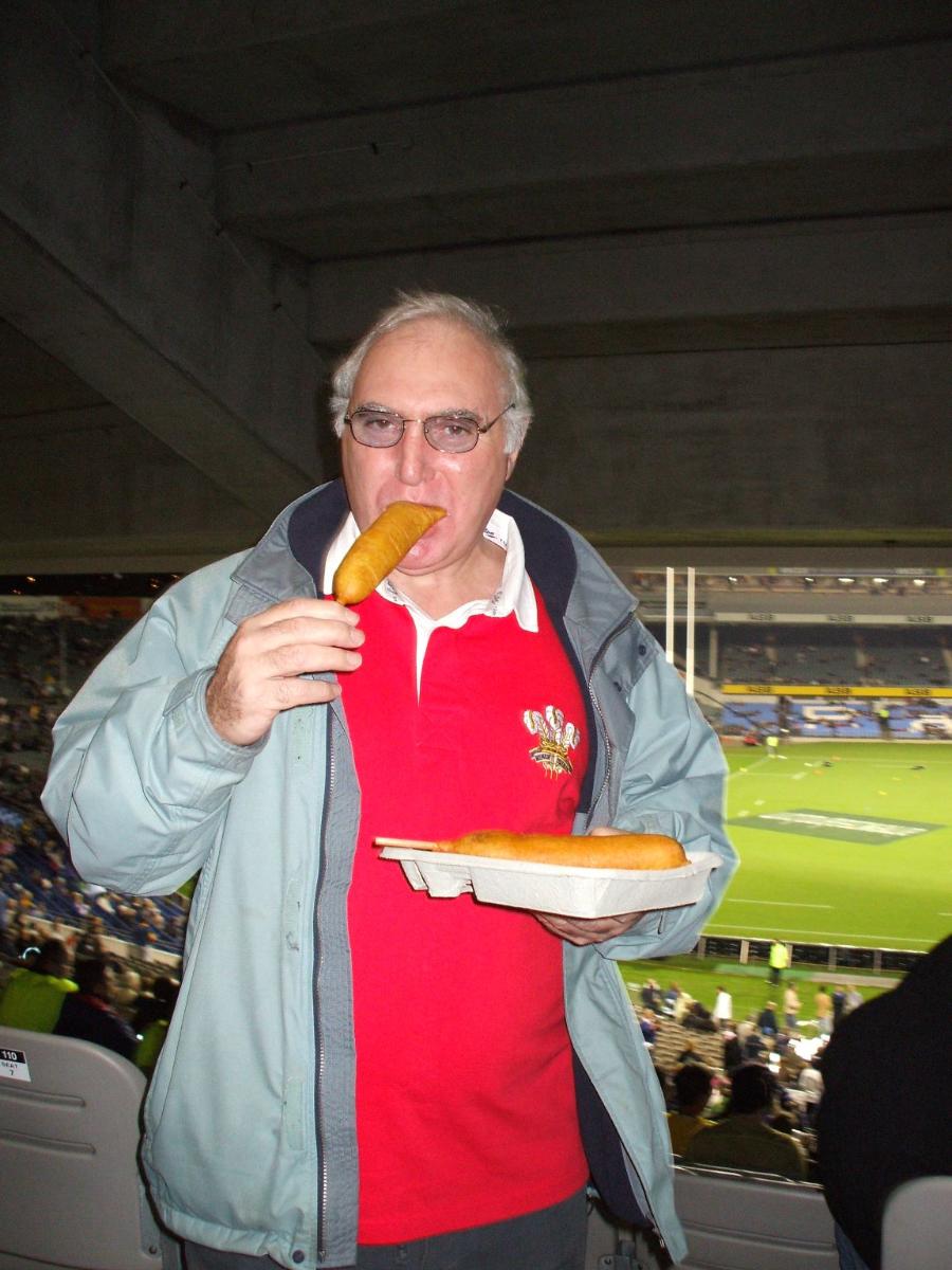 Keith (wearing his Welsh Rugby shirt) tries a NZ hotdog at the game.